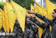 A masked demonstrator waves a flag of the Lebanese Shiite movement Hezbollah during a demonstration