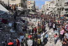 People gather around the rubble of a house destroyed in an Israeli strike as rescuers search for casualties on al-Jalaa street in central Gaza City