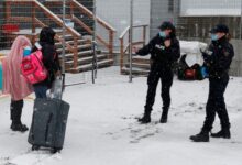 Royal Canadian Mounted Police officers greet refugees as they arrive at the Roxham Road border crossing in Champlain, New York in 2023