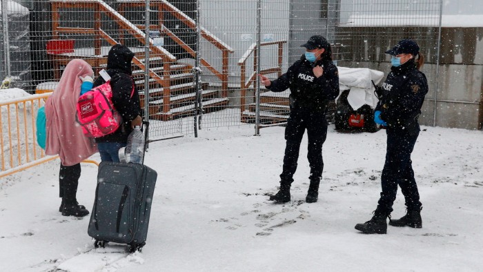 Royal Canadian Mounted Police officers greet refugees as they arrive at the Roxham Road border crossing in Champlain, New York in 2023