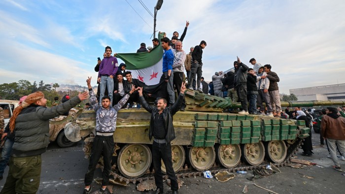 People celebrate on top of an armoured tank with anti-government fighters in Damascus