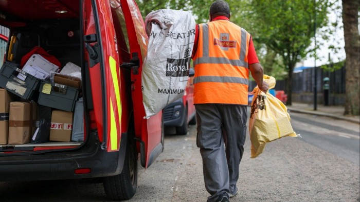 A post worker loads a Royal Mail van